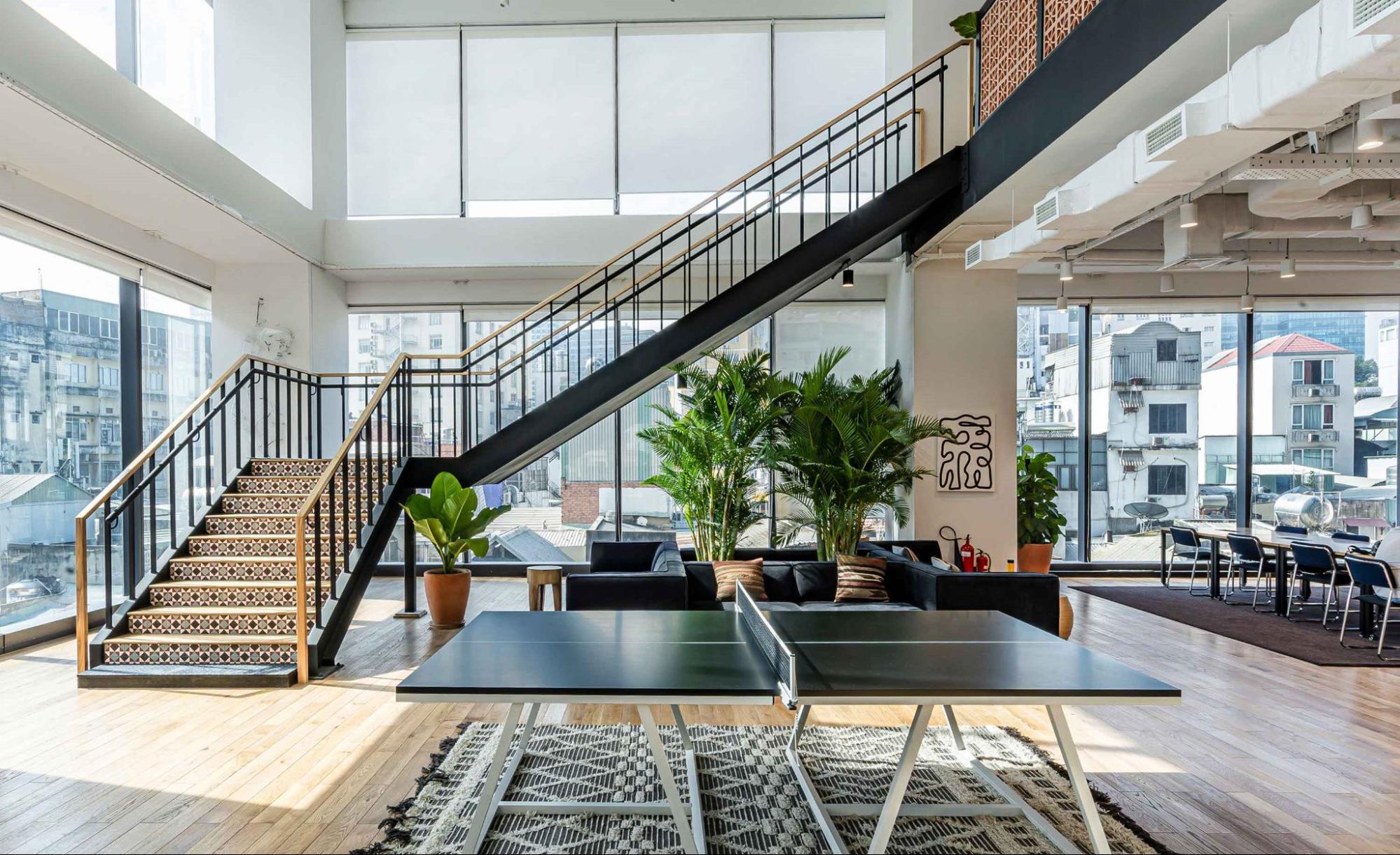 Spacious coworking area with a staircase, plants, and a ping pong table.