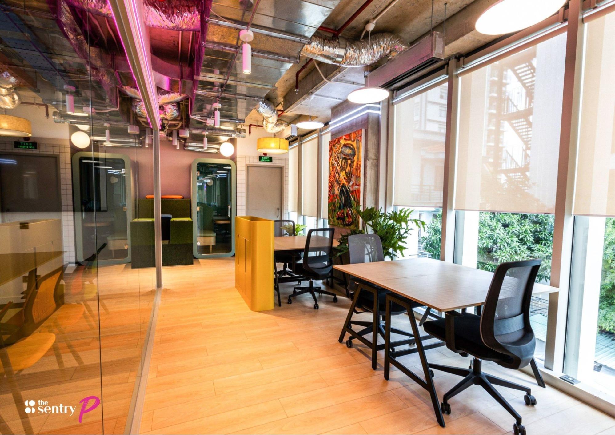 A modern hybrid workplace model with large windows, natural light, and colorful decor.