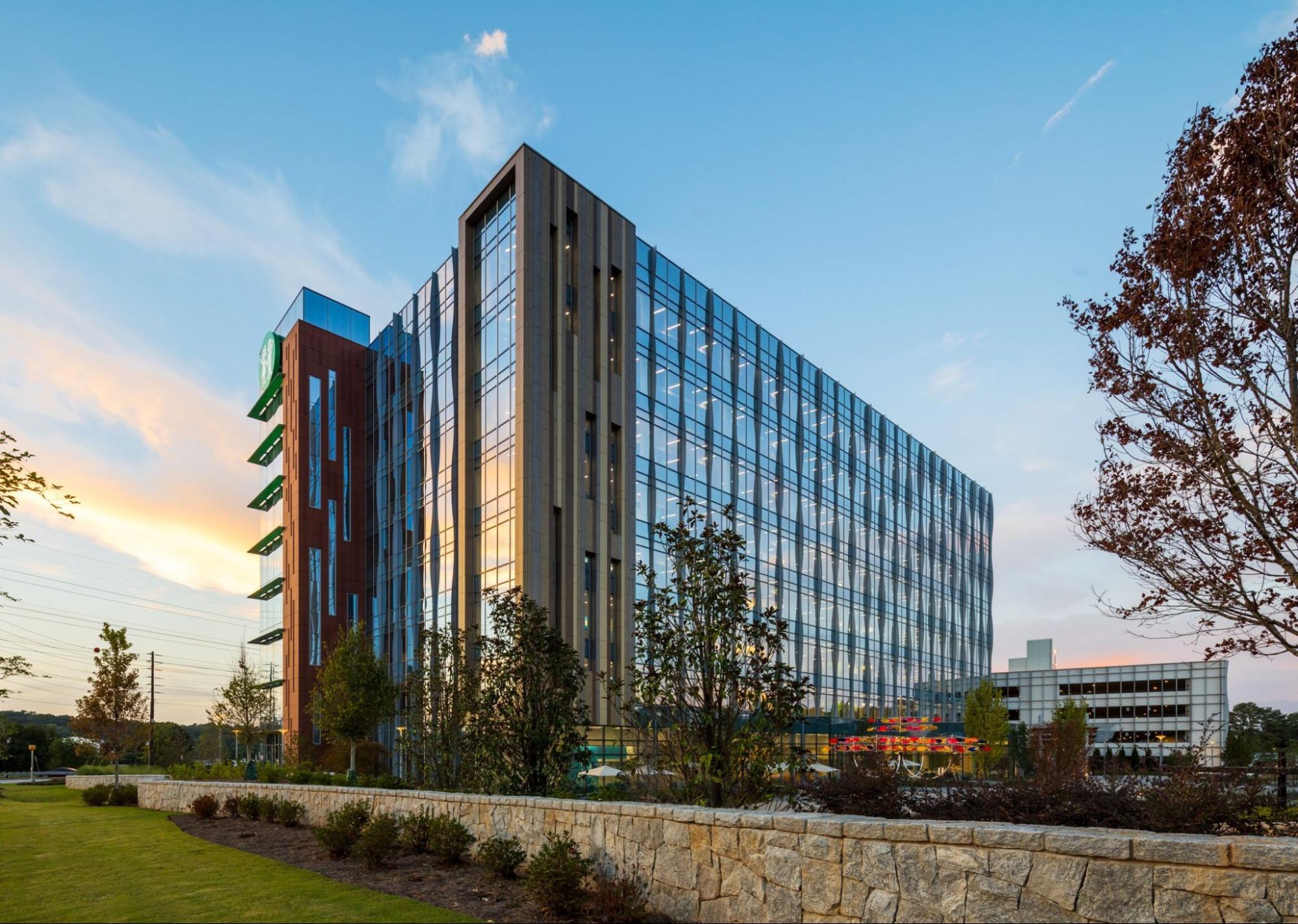 A contemporary office building with glass windows and green surroundings.