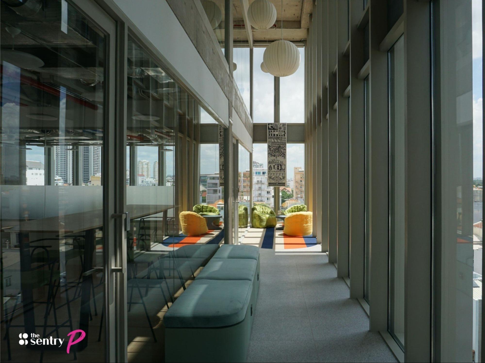 A hallway in a coworking space with large windows and seating areas.