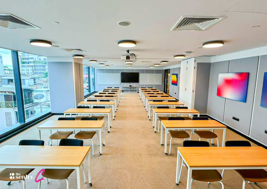 A modern conference room featuring a large screen with a video conferencing system active.