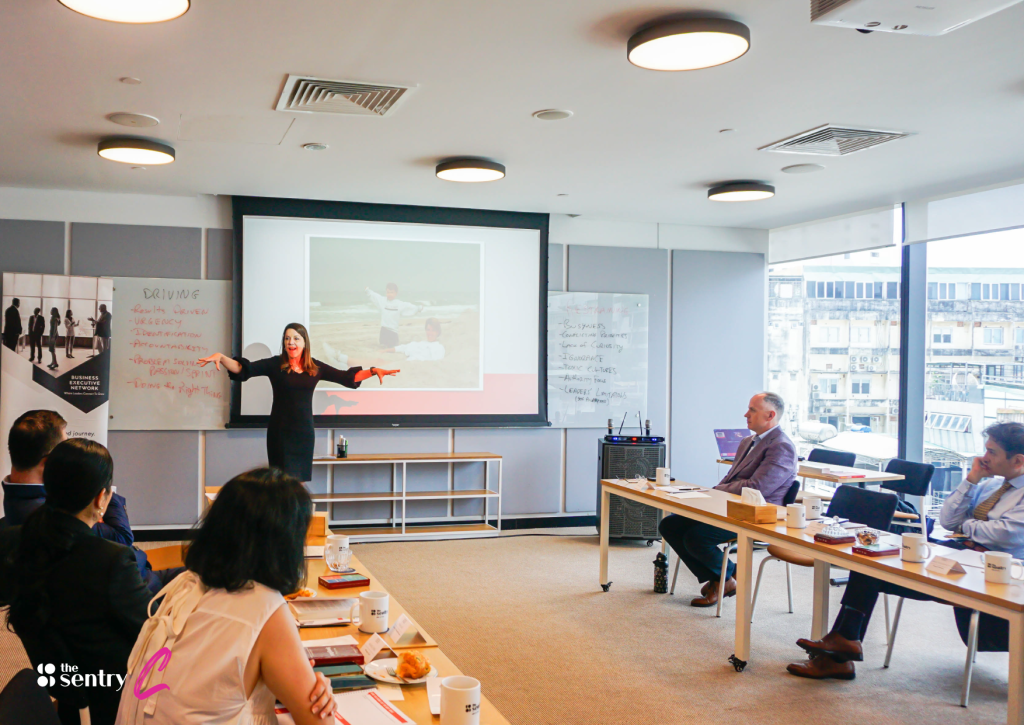 A presenter speaking to an engaged audience in a corporate conference room setup.