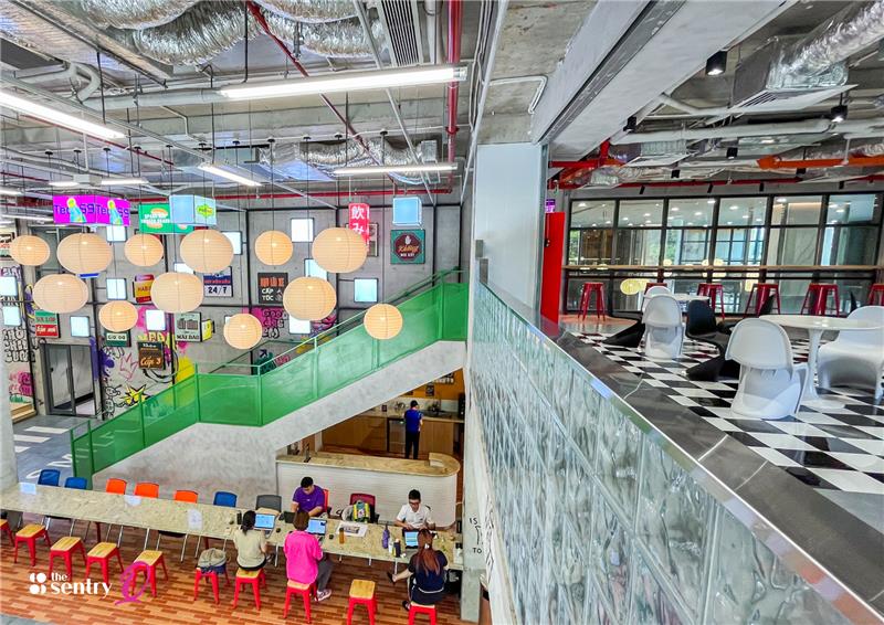 Freelancer typing on a laptop at a communal wooden table.