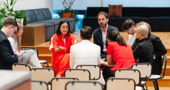 Serious business discussion inside a glass-walled modern meeting room.