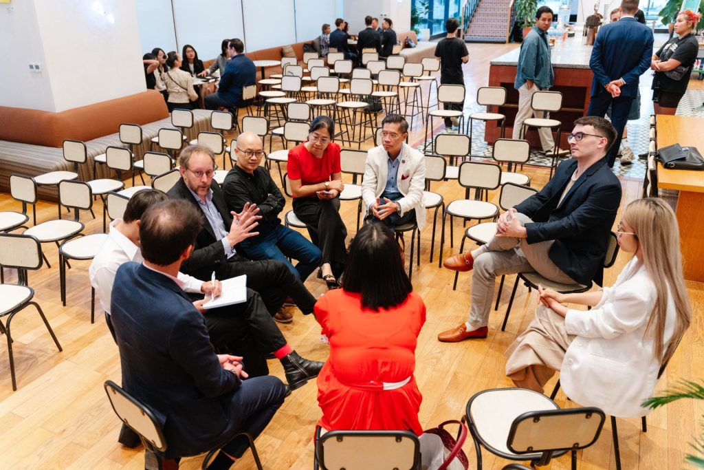 A group of people brainstorming around a table in a glass-walled meeting room.