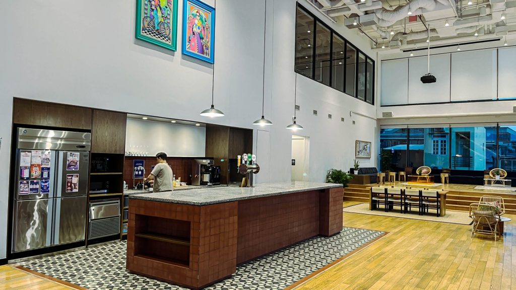 Modern office pantry with coffee machine and seating.