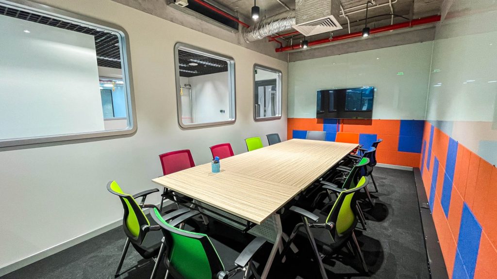 A sleek, modern meeting room featuring a large table, ergonomic chairs, and a presentation screen.