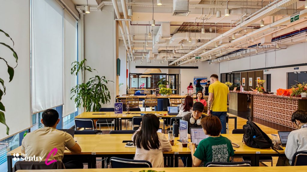 Professionals working at desks in a bright, open coworking floor