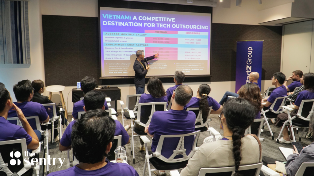A professional leading a presentation in a glass-walled conference room.