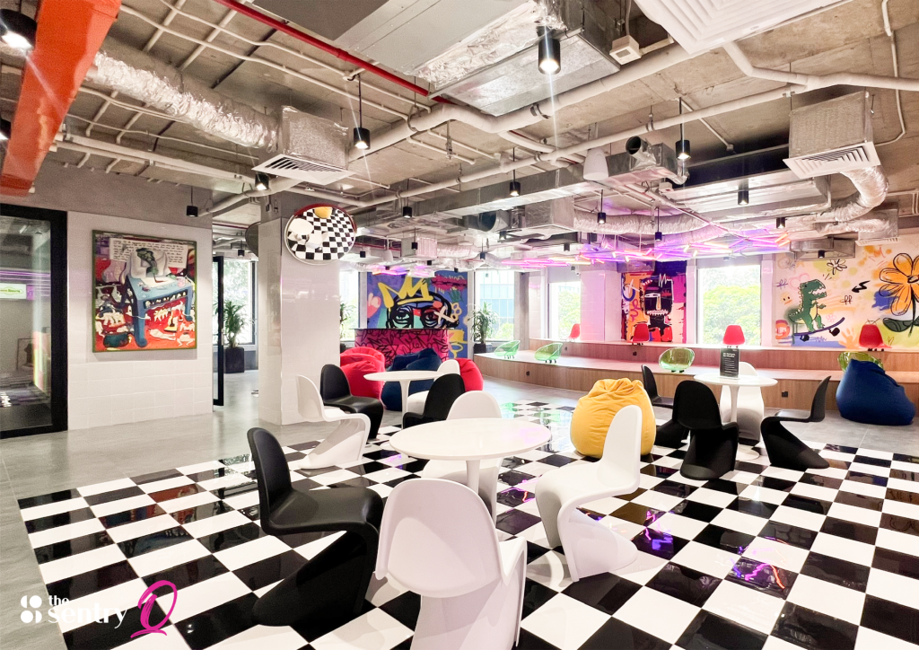 A wide view of a vibrant coworking space featuring hot desks, private offices, and a networking lounge.