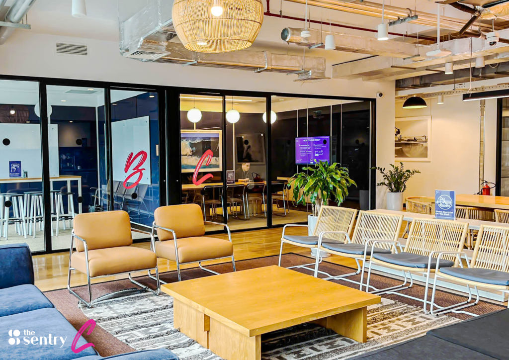 A wide-angle view of a design-led coworking floor featuring hot desks, lounge seating, and private offices.