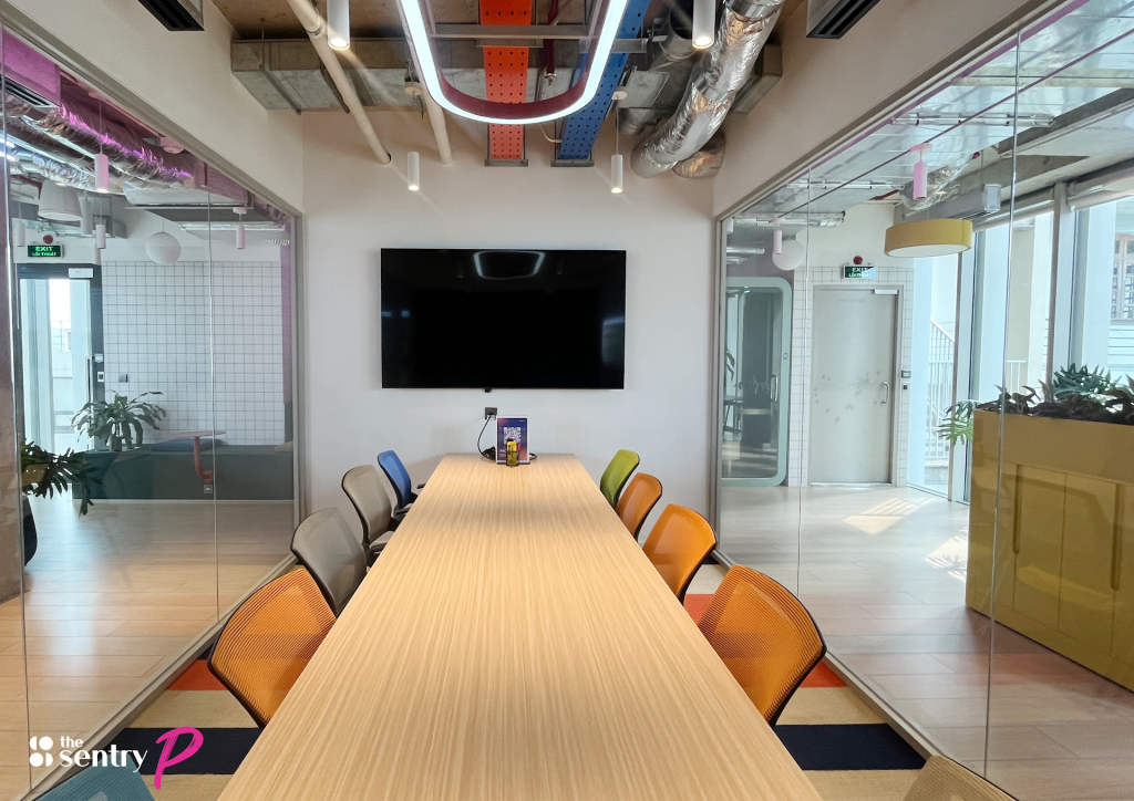Glass-walled meeting room with a table and screen at The Sentry